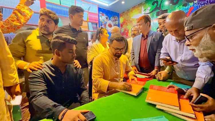 চলন্তিকায় নিজ বইয়ে অটোগ্রাফ দিচ্ছেন আমিনুল